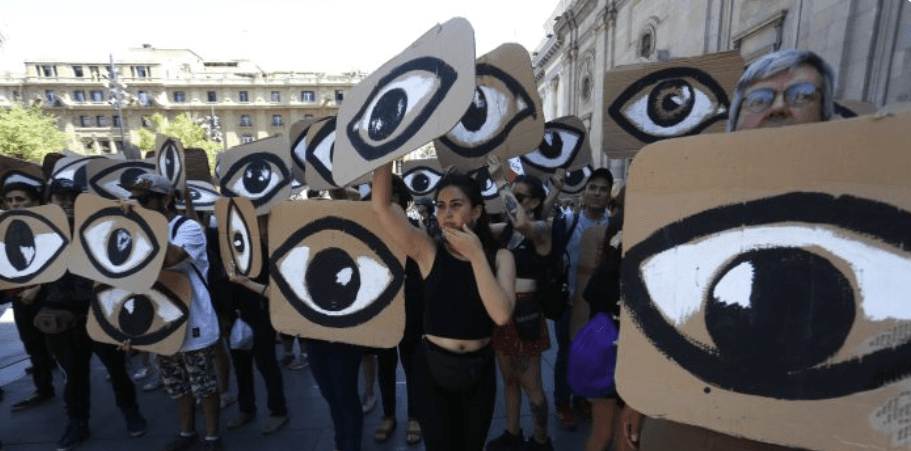 Manifestantes en una plaza de Chile sostienen carteles de cartón con ojos pintados